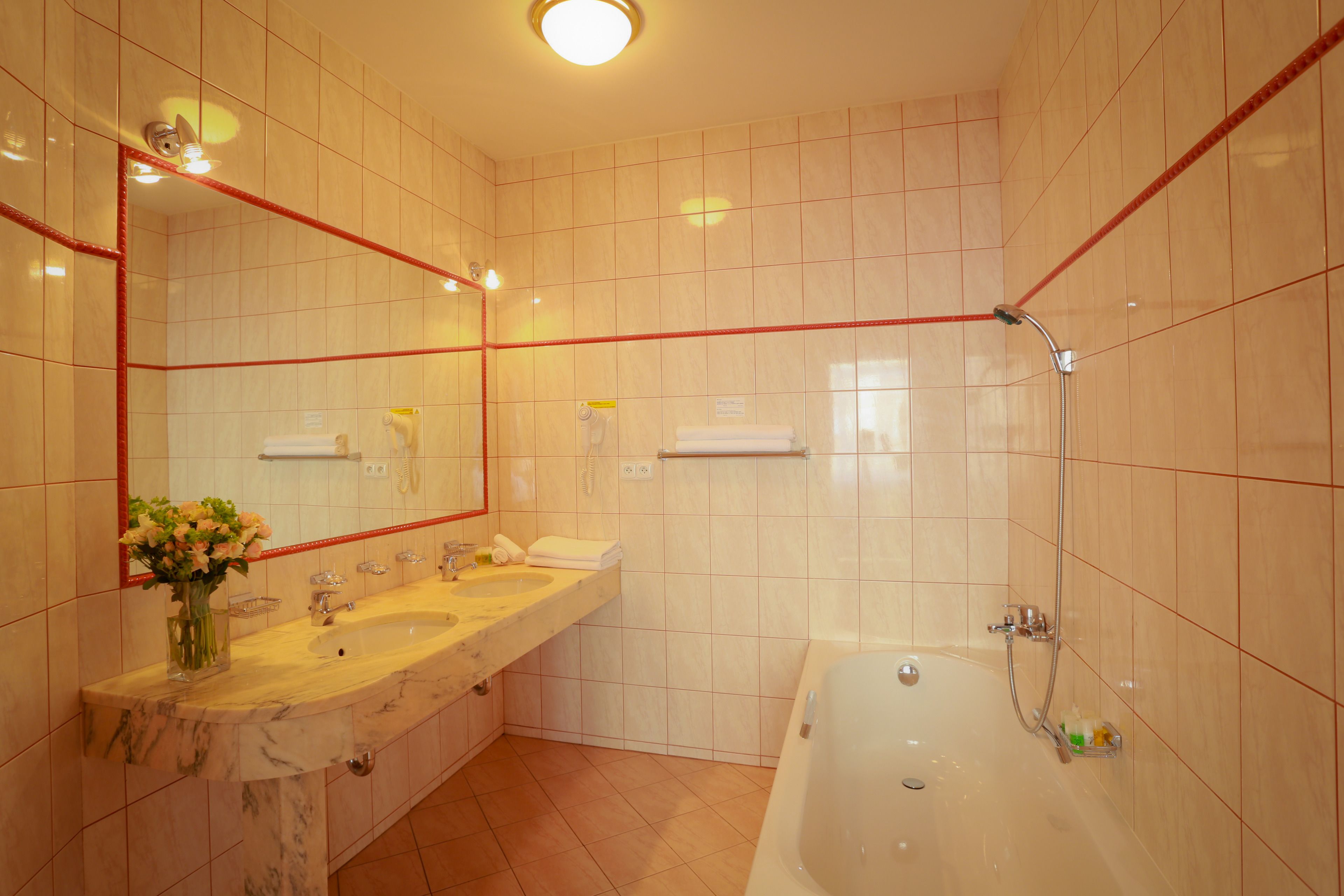 Een badkamer met twee wastafels, een spiegel, een bad en een douche.