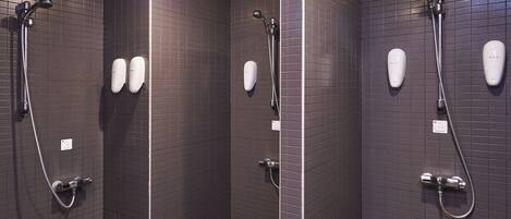 A bathroom with three shower stalls, each equipped with a handheld showerhead and a handheld shower attachment.