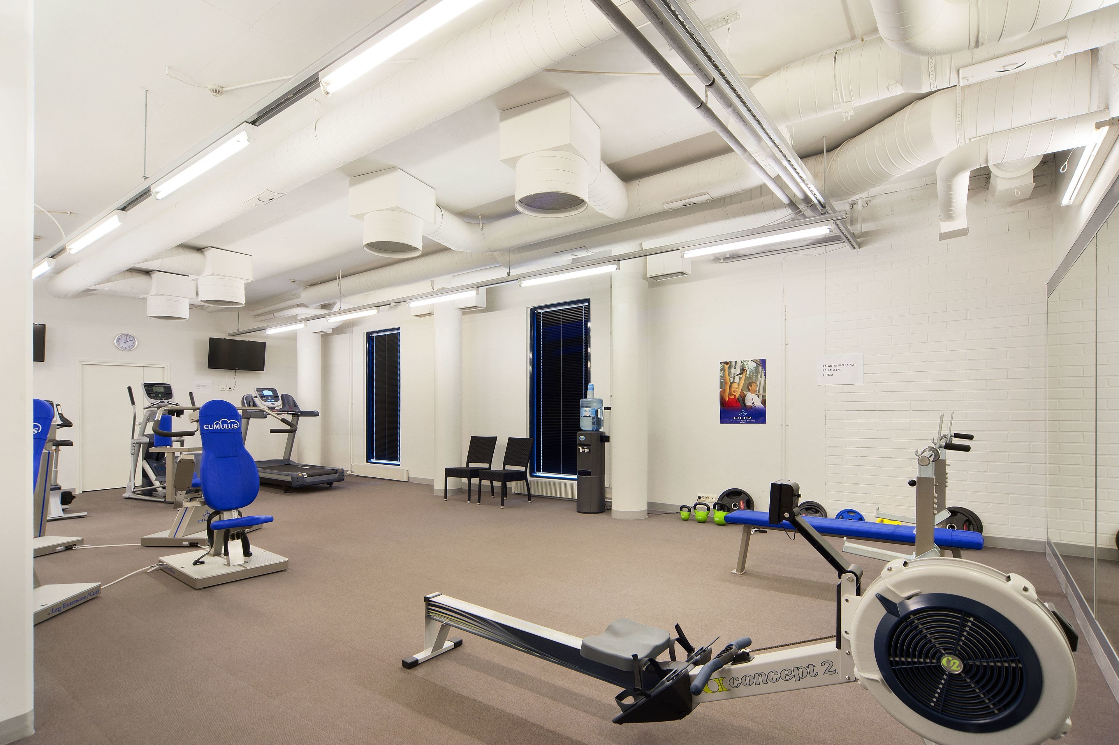 A gym with cardio machines, weightlifting equipment, and a rowing machine.