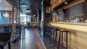 A bar area with wooden flooring, bar stools, and a counter with taps. - Scandic Jyväskylä City (Jyväskylä)