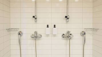 Un baño con tres cabezales de ducha, un perchero y un dispensador de jabón.