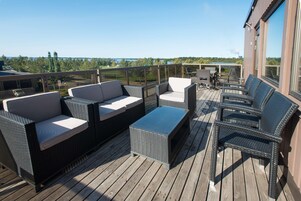 Una terraza con mobiliario de mimbre, incluyendo sofás y sillones, con vistas panorámicas.