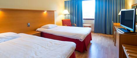 Habitación de hotel con dos camas, un escritorio con televisor, una silla y una ventana con cortinas.