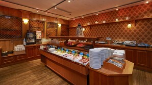A buffet with various food options, wooden decor, and a patterned wall.