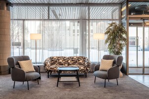 Un hall moderno con un sofá, sillones, una mesa de centro y una planta grande.