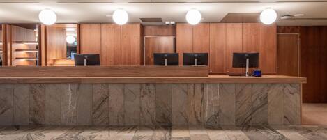 A reception area with a marble floor, wooden paneling, and three computer monitors.