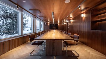 A conference room with a long table, chairs, and a large window overlooking a snowy landscape.