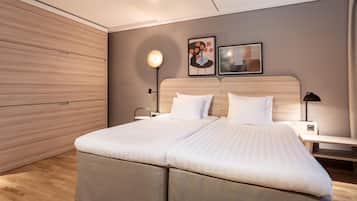 A modern bedroom with a large bed, wooden paneling on the walls, two bedside tables with lamps, and artwork on the wall.