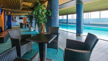 A poolside area with wicker furniture, a potted plant, and a view of the pool.