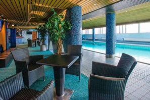 A poolside area with wicker furniture, a potted plant, and a view of the pool.