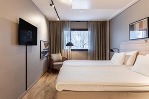 A hotel room with a bed, a chair, a TV, and a window with curtains. - Scandic Pohjanhovi (Rovaniemi)