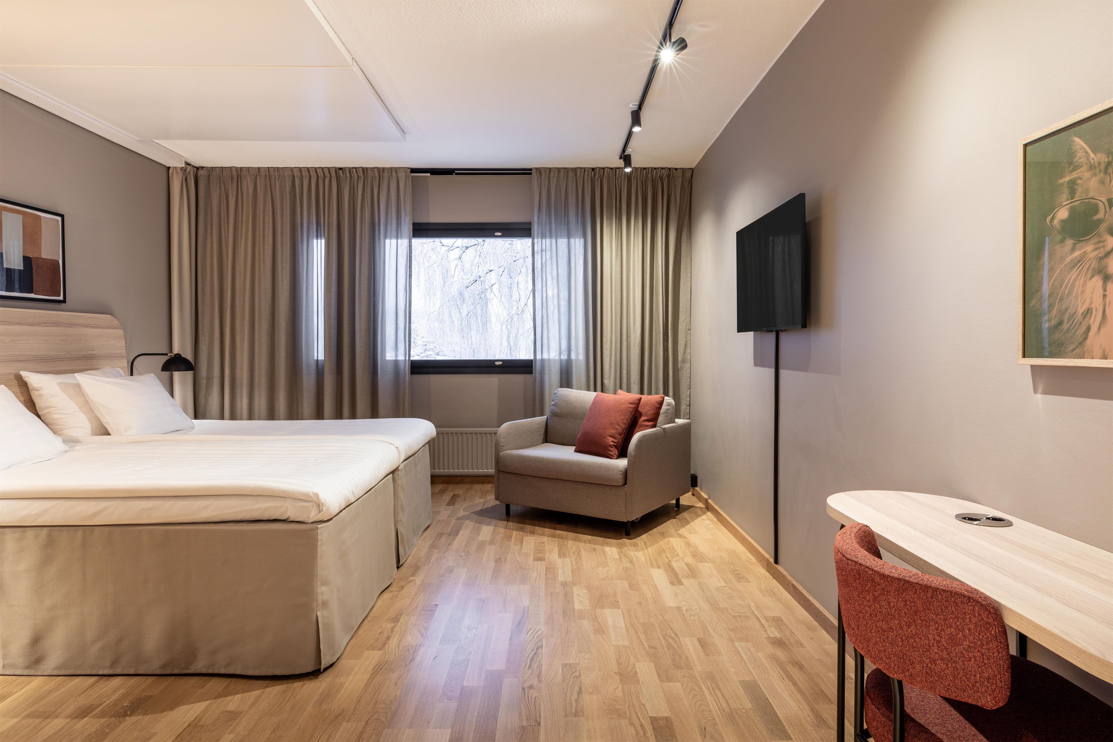 A hotel room with a bed, a sofa, a desk, and a TV.