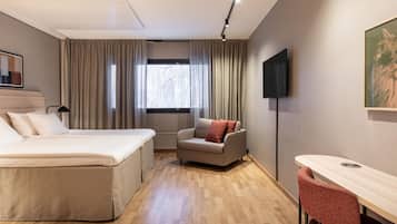 A hotel room with a bed, a sofa, a desk, and a TV.
