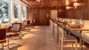 A modern restaurant with wooden paneling, large windows, and a long dining table with chairs. - Scandic Pohjanhovi (Rovaniemi)