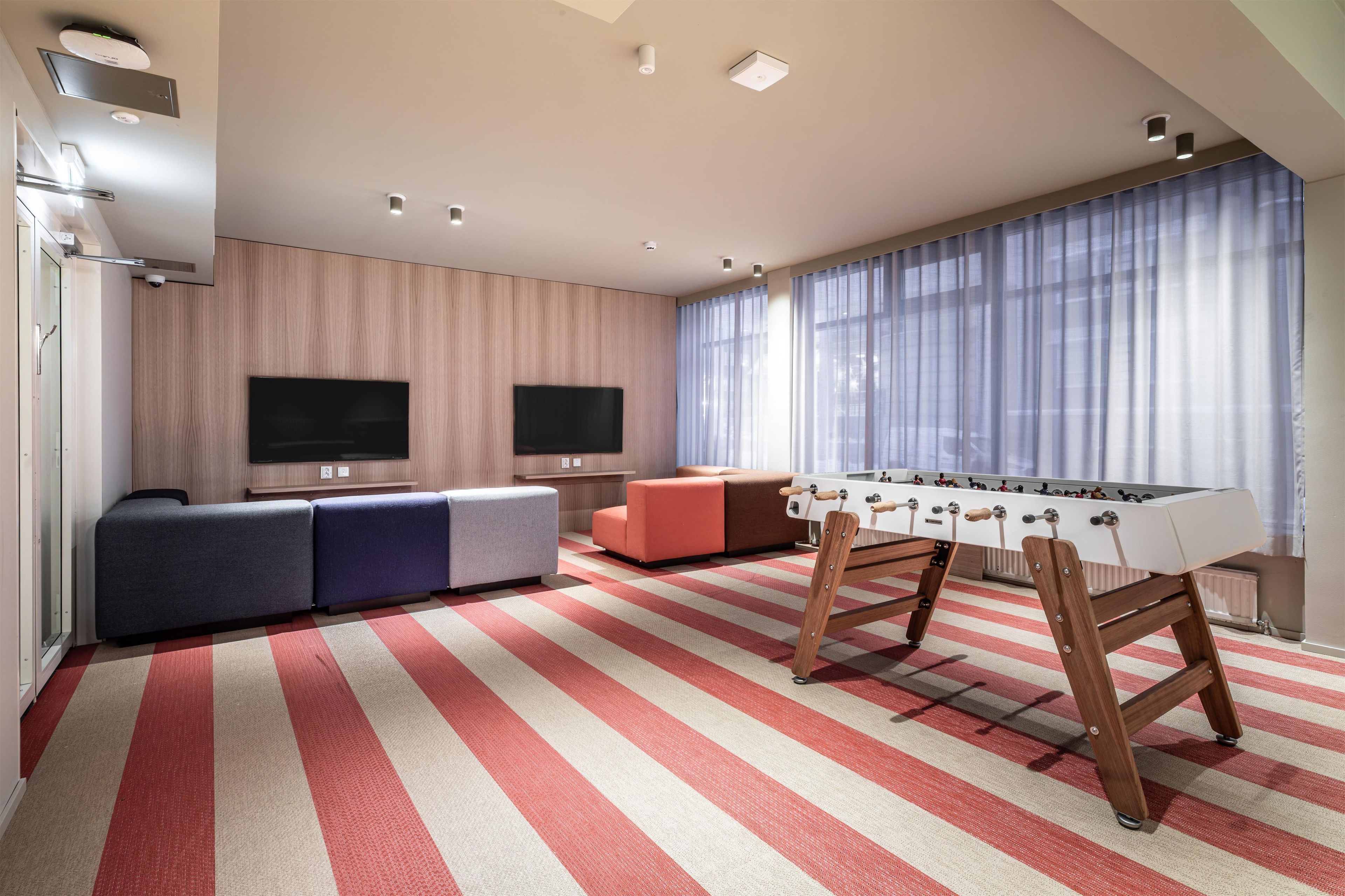 A modern living room with a foosball table, a sofa, and a TV.