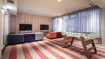 A modern living room with a foosball table, a sofa, and a TV.