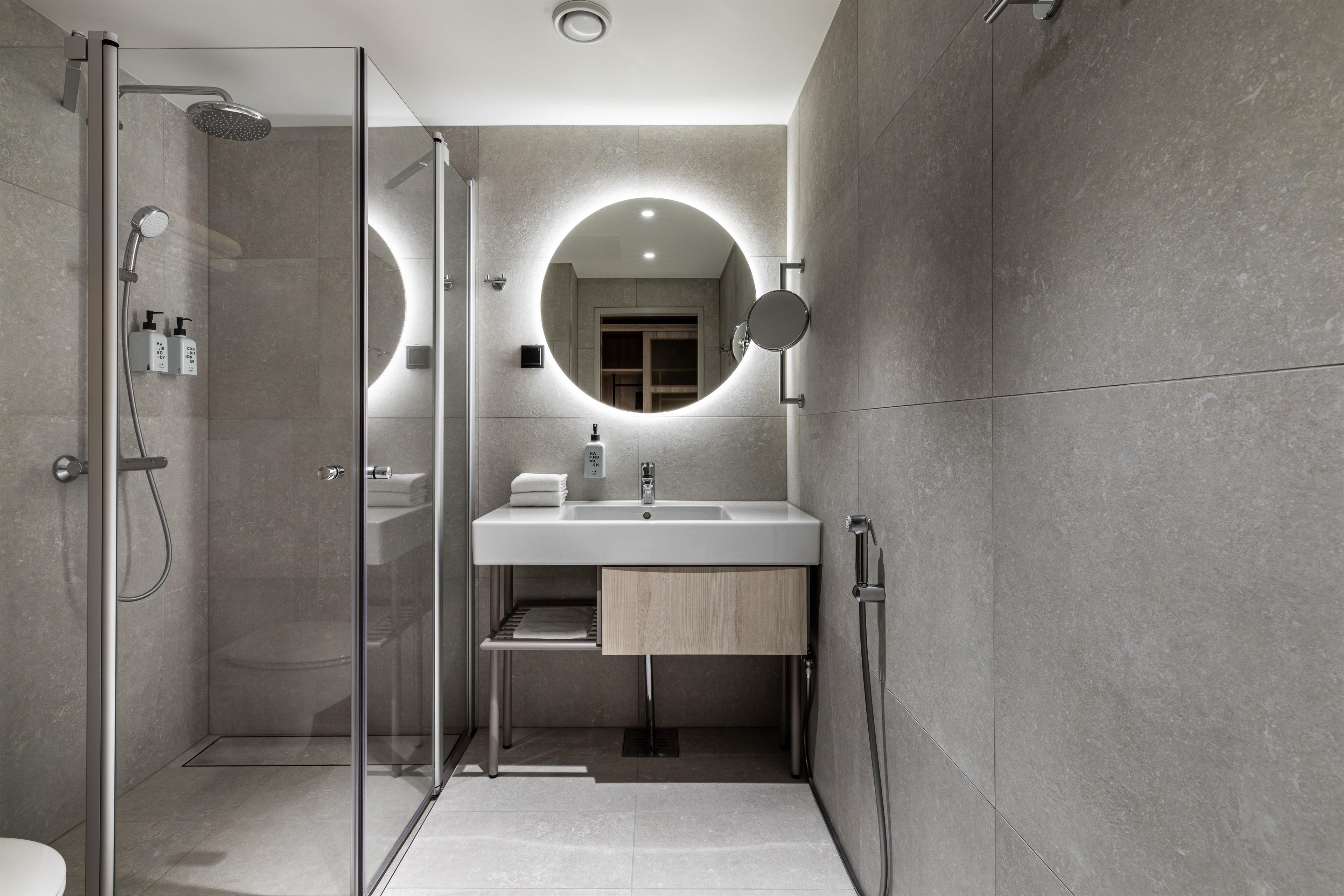 Un baño moderno con ducha de vidrio, lavabo con espejo y barra para toallas.