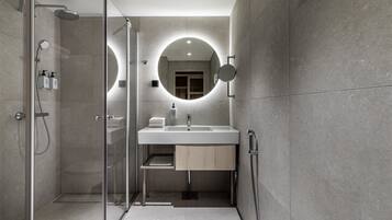 Un baño moderno con ducha de vidrio, lavabo con espejo y barra para toallas.