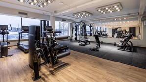 A gym with cardio machines, weightlifting equipment, and large windows offering a view of the outdoors. - Scandic Pohjanhovi (Rovaniemi)