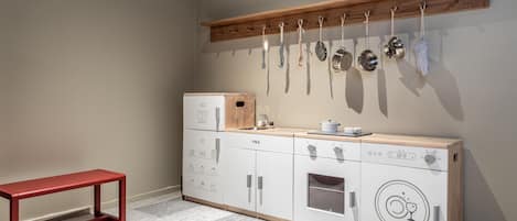 A compact kitchen with a wooden countertop, a built-in oven, and a hanging pot rack.