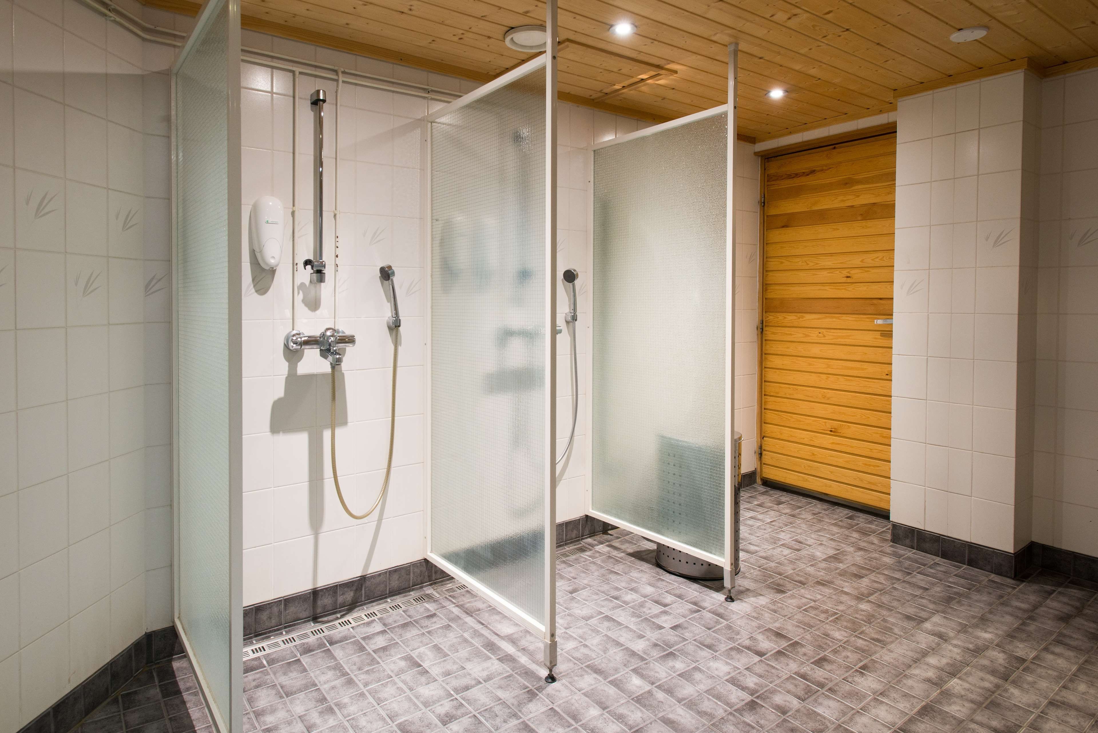 A shower area with frosted glass doors, a wooden ceiling, and a tiled floor.