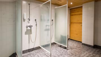 A shower area with frosted glass doors, a wooden ceiling, and a tiled floor.