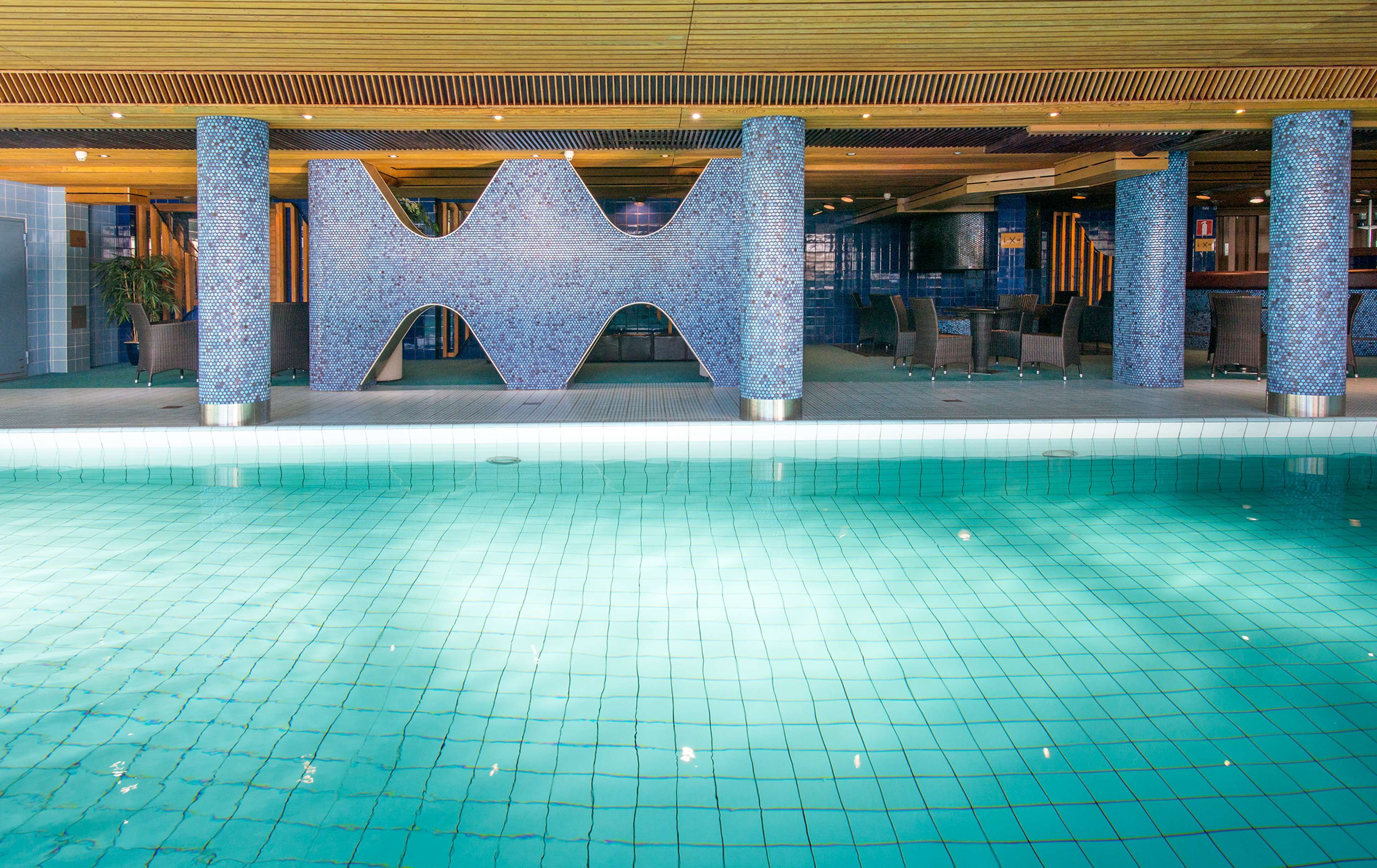 A swimming pool with a tiled floor and a decorative structure with a geometric design.