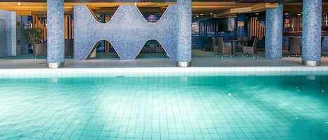 A swimming pool with a tiled floor and a decorative structure with a geometric design.