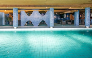 En swimmingpool med ett kaklat botten och en dekorativ konstruktion med ett geometriskt mönster.