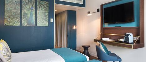 A hotel room with two beds, a TV, a desk with a coffee machine, and artwork on the wall.