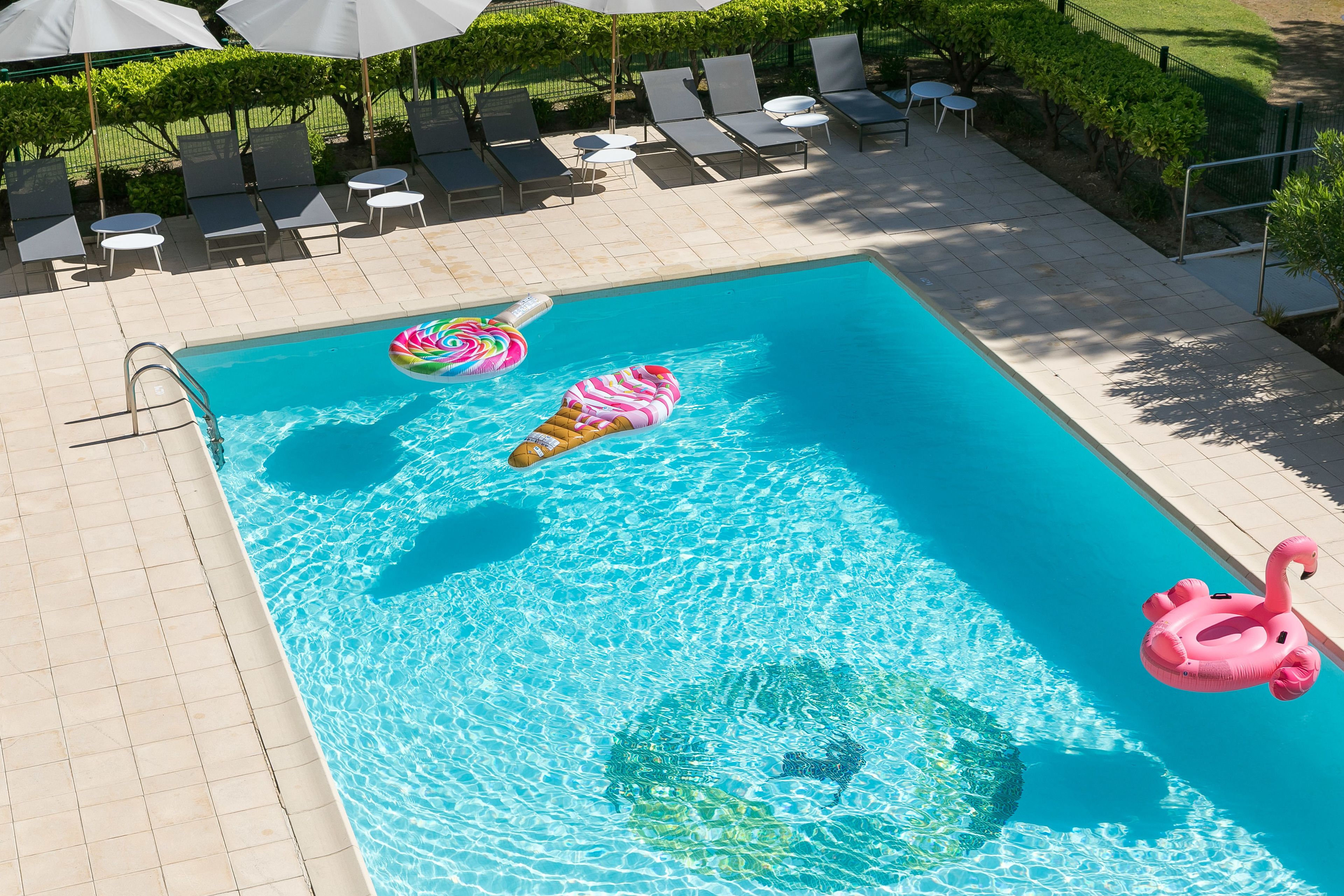 Una piscina con sillones de descanso y sombrillas.