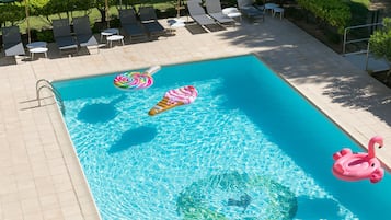 Una piscina con sillones de descanso y sombrillas.