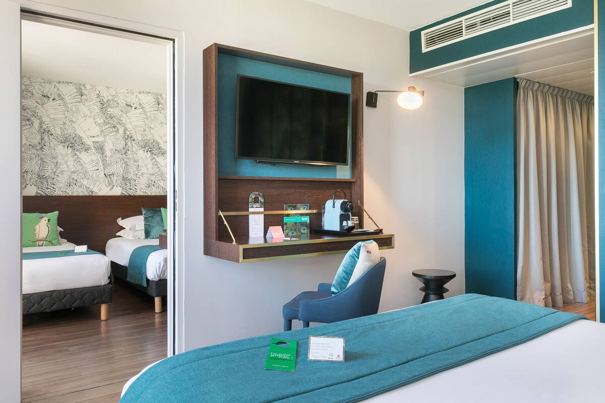 Une chambre d’hôtel avec deux lits, un bureau doté d’un téléviseur à écran plat, une petite table et une chaise.