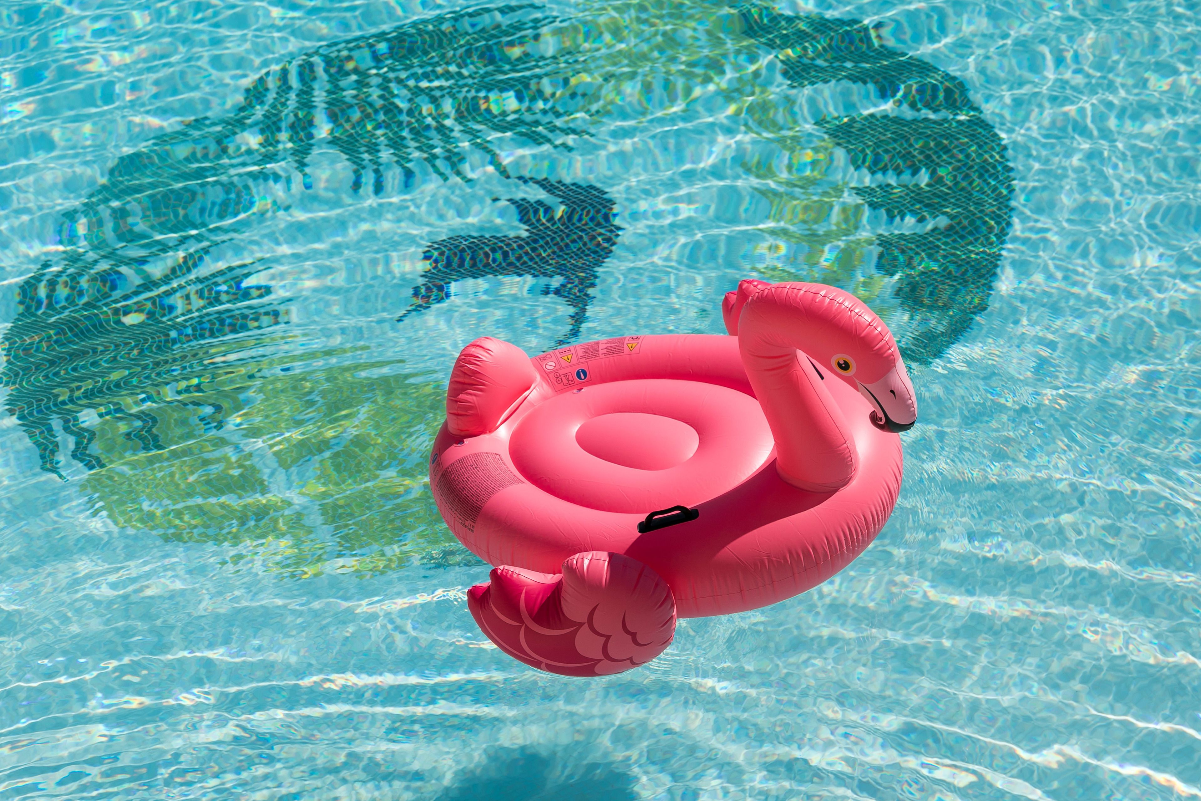 Un flamenco inflable rosa en una piscina azul cristalina.