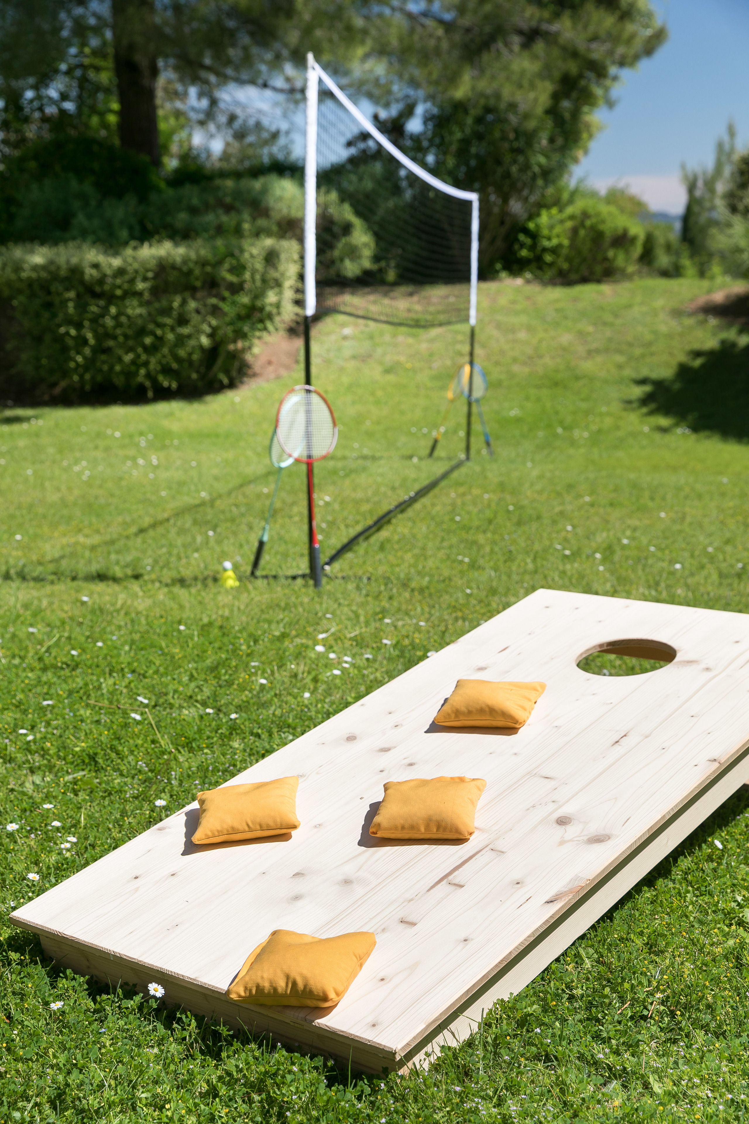 Un juego de mesa de madera con cojines y una red de bádminton en un césped.