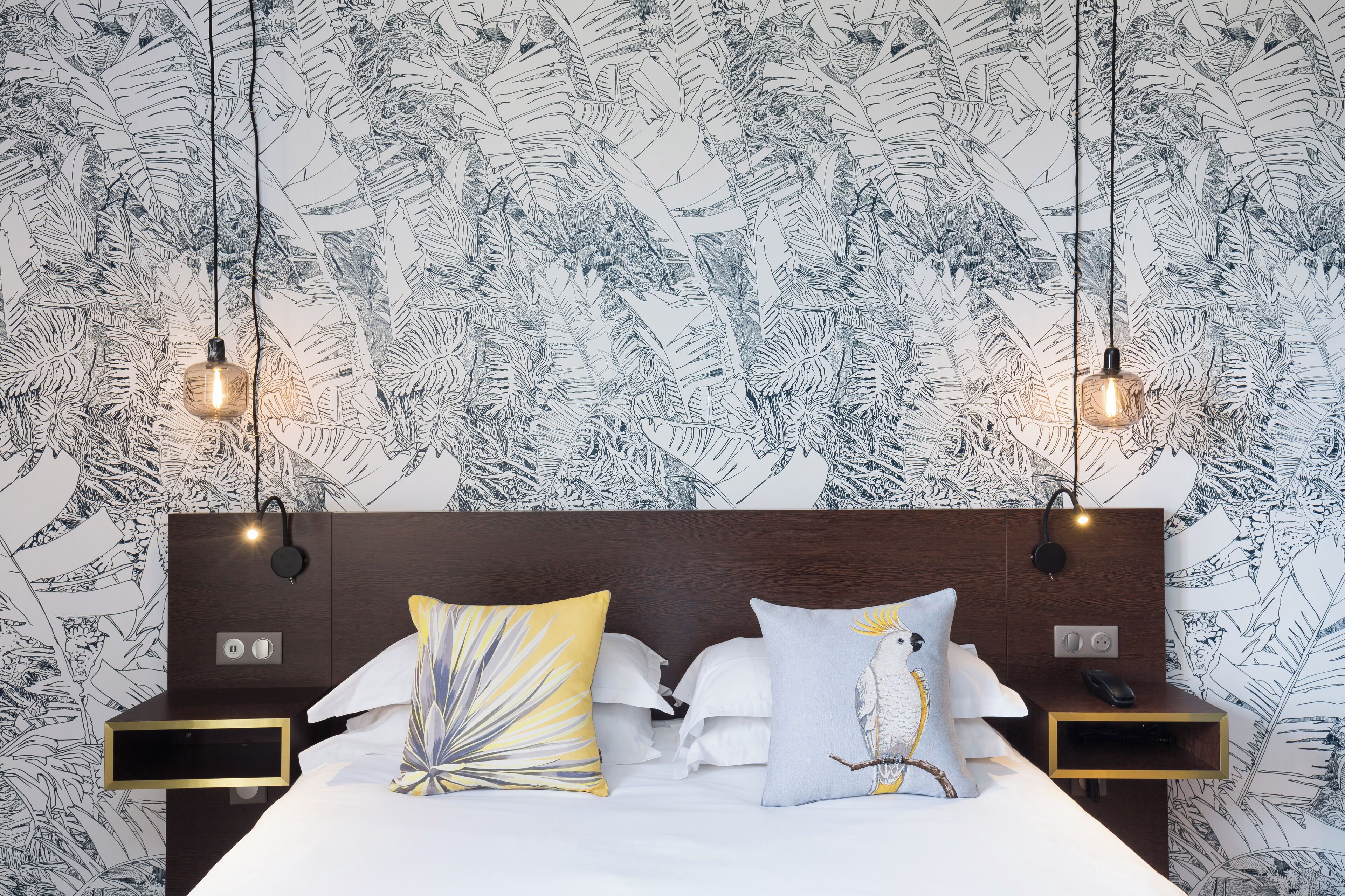 Een hotelkamer met een bed, twee nachtkastjes en een hoofdeinde.
