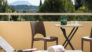 Un balcon avec une table, des chaises, un magazine, une serviette et une boîte décorée de motifs d’oiseaux.