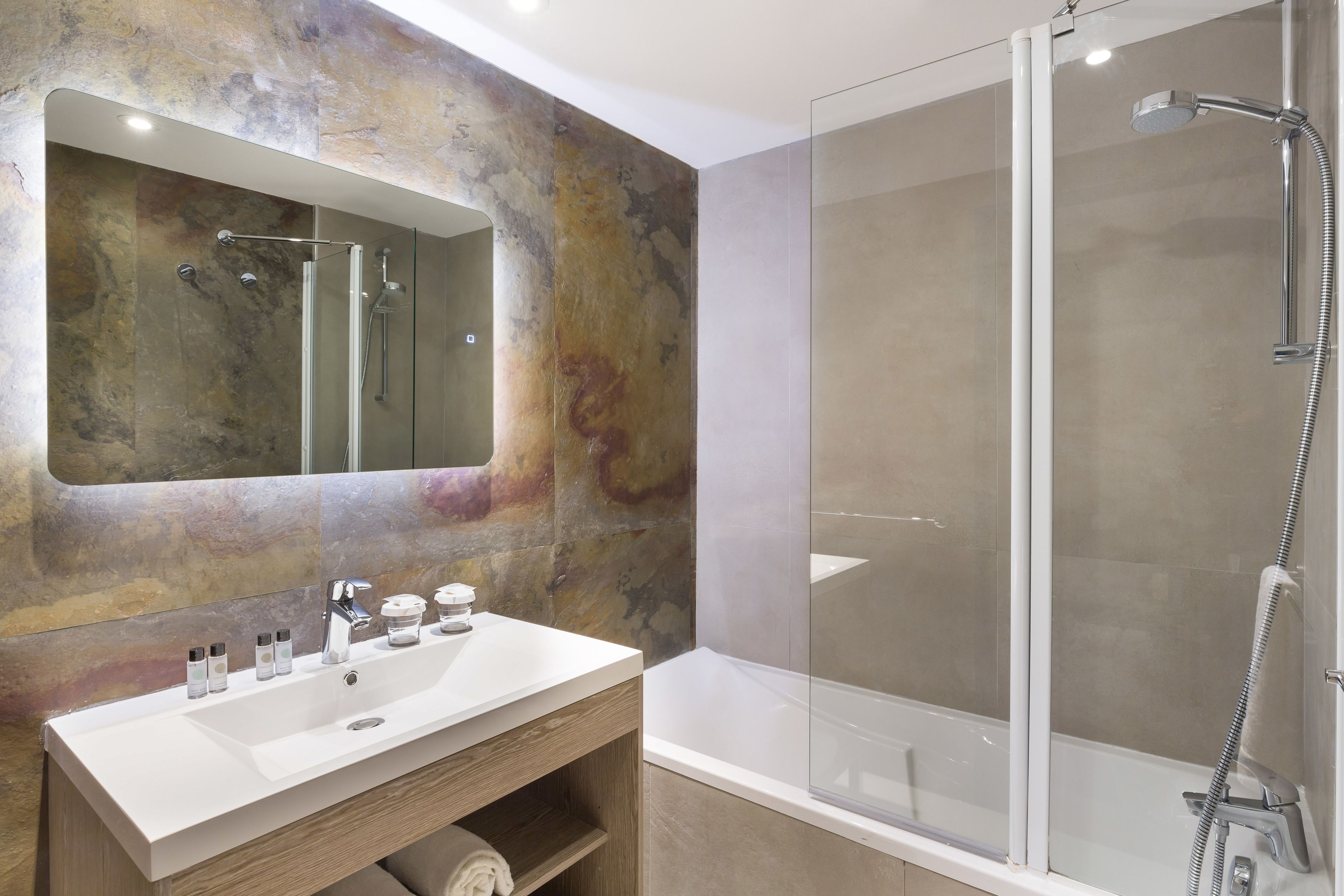 A modern bathroom with a large mirror, a white sink, and a glass-enclosed shower area.