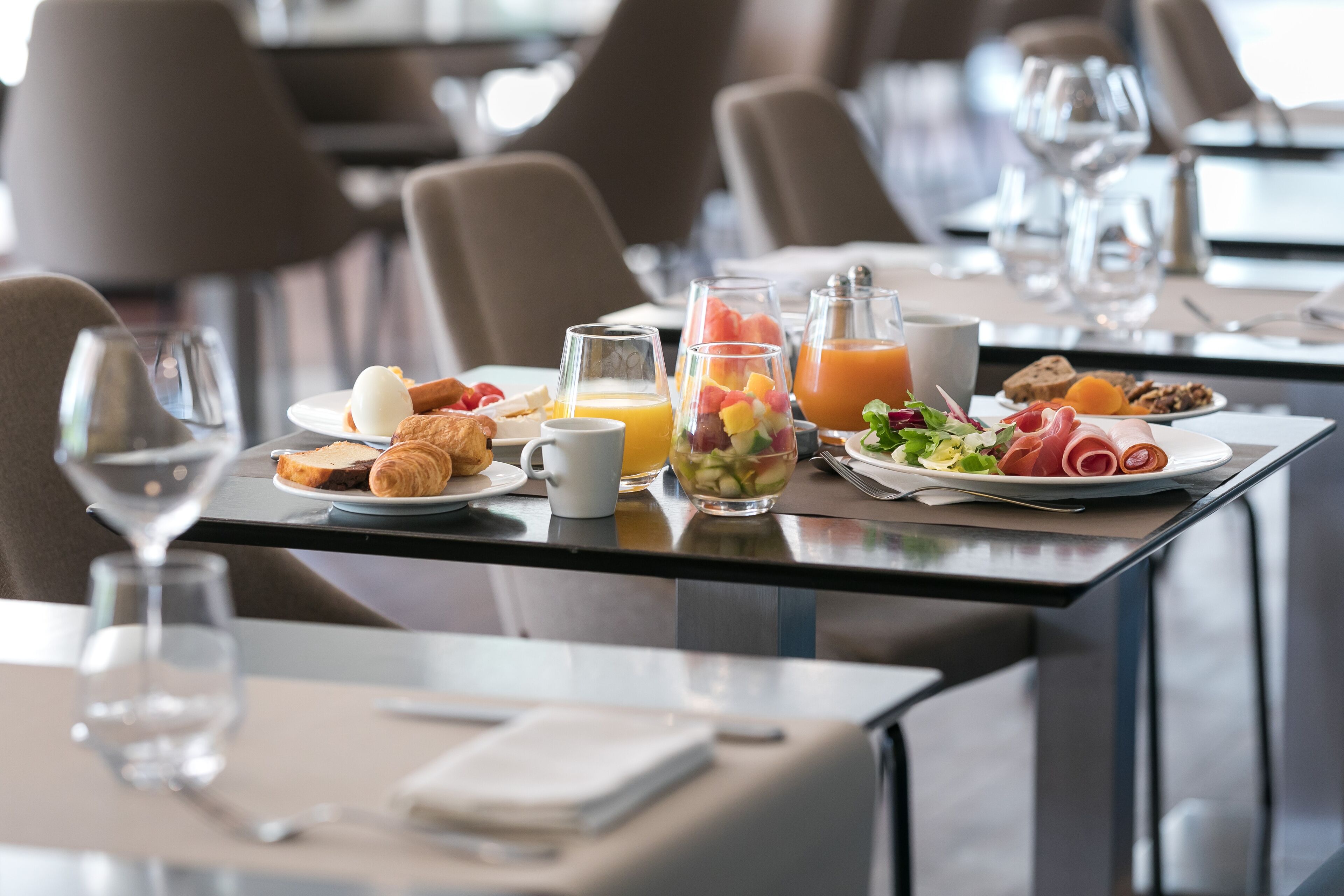 Une table dressée pour le petit-déjeuner, avec des croissants, des œufs, des fruits et du jus.