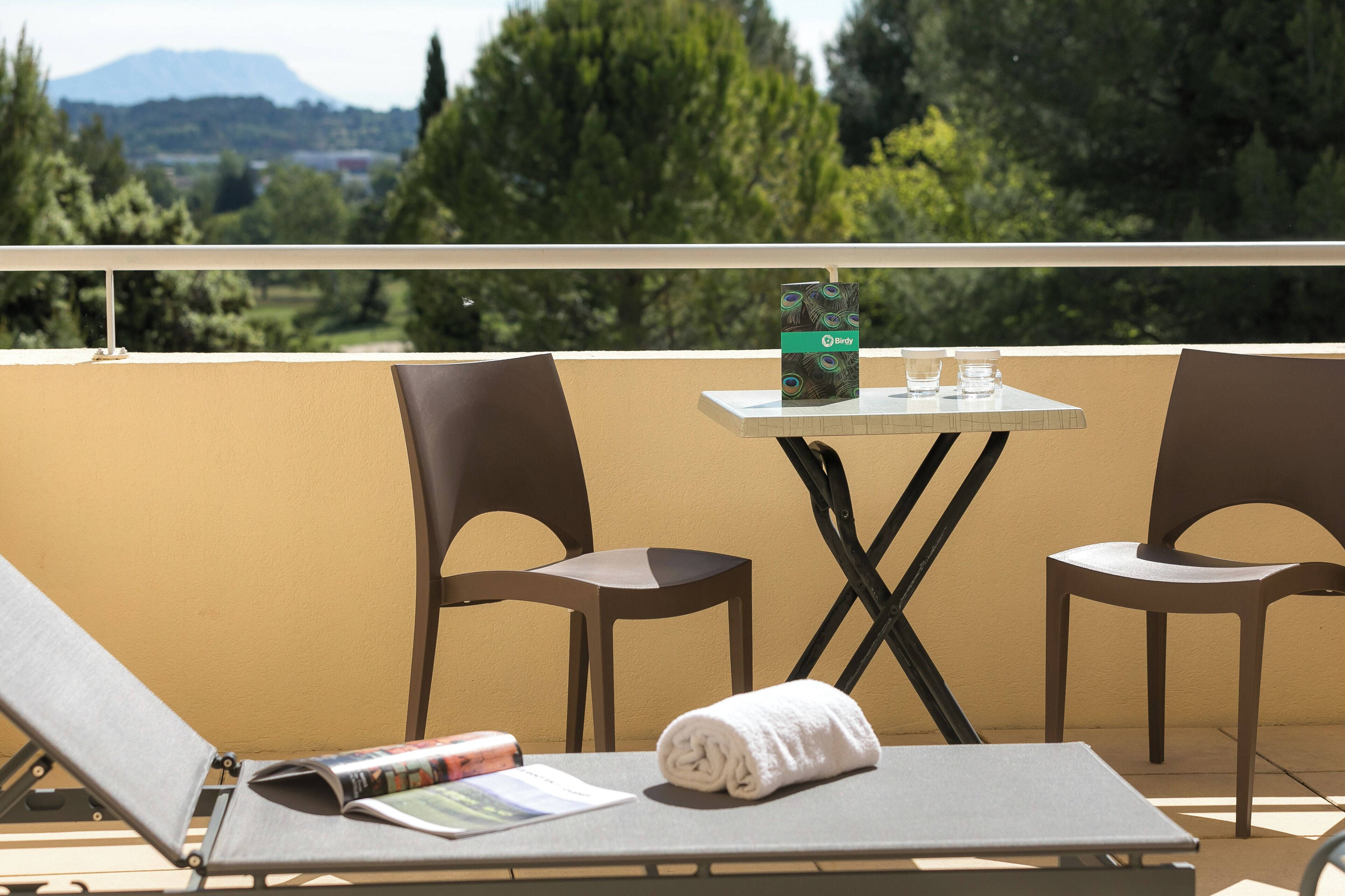 A balcony with two chairs, a small table, and a magazine.