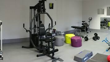 Une salle de sport équipée de divers appareils d’exercice, notamment un tapis de course, des appareils de musculation et un rameur.