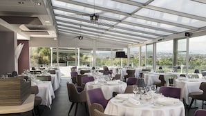 Un restaurante moderno con mesas redondas, manteles blancos y sillas moradas.