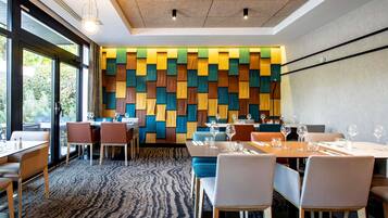L’intérieur d’un restaurant moderne, avec un mur orné de motifs, des tables avec des chaises et un sol recouvert de moquette.