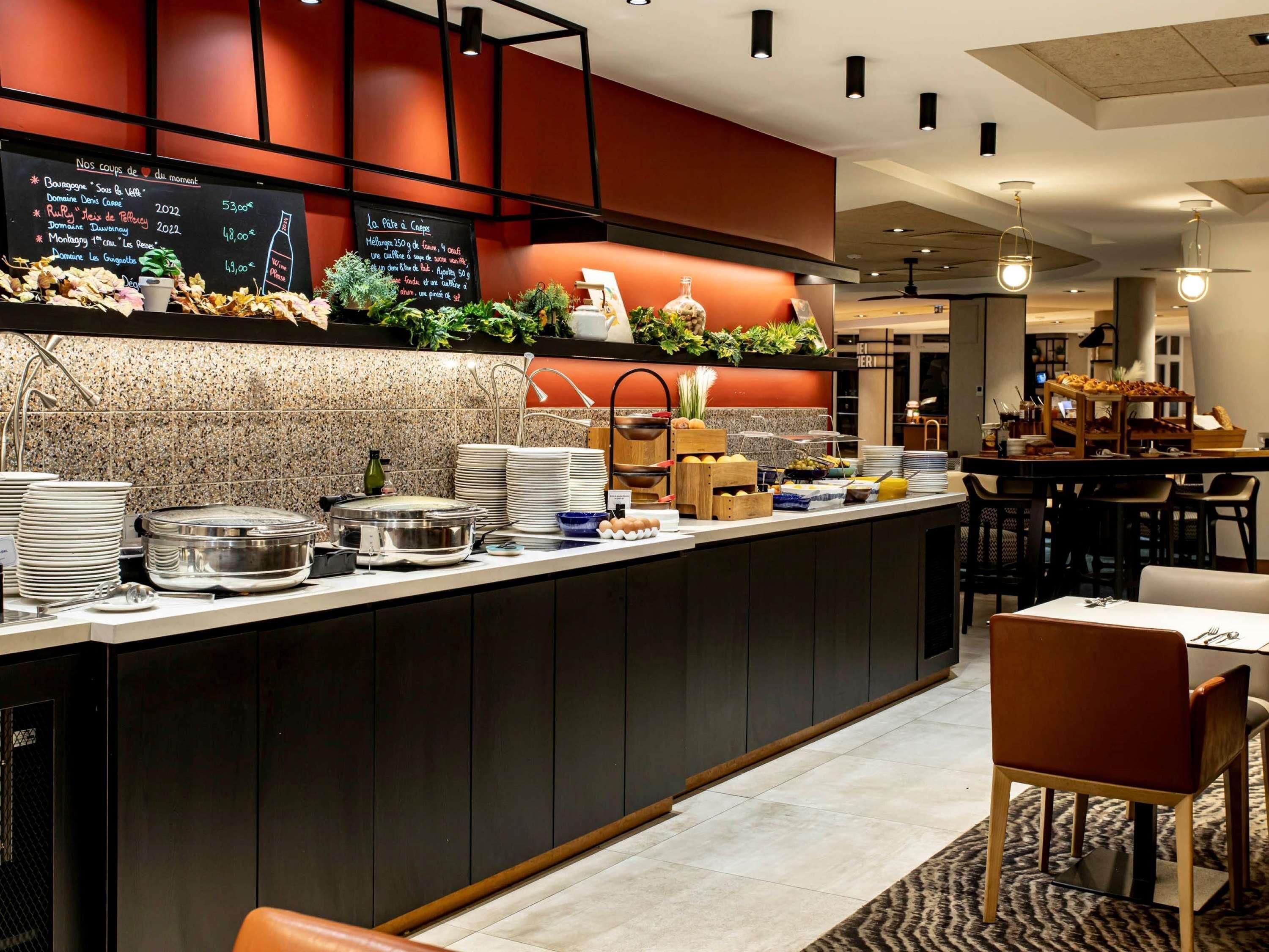 Un bar à petit-déjeuner moderne, doté d’un tableau noir servant de menu, d’assiettes empilées et de divers aliments.