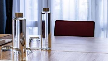 A wooden table with clear glass bottles and a metal container, a red chair, and a window with curtains.