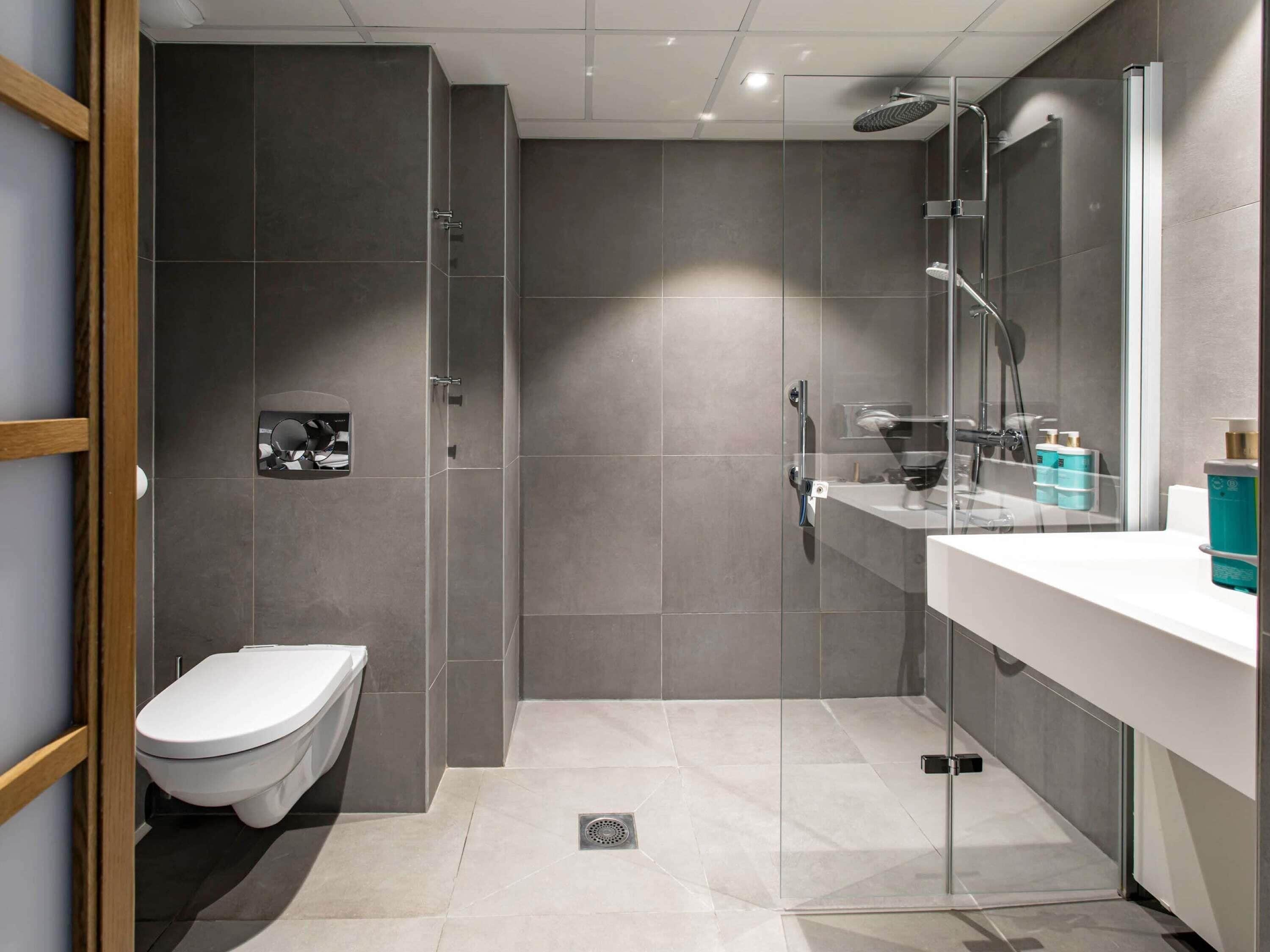 A modern bathroom with a toilet, a glass shower enclosure, and a vanity with a mirror.