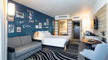 A hotel room with a bed, a sofa, a desk, and a TV.