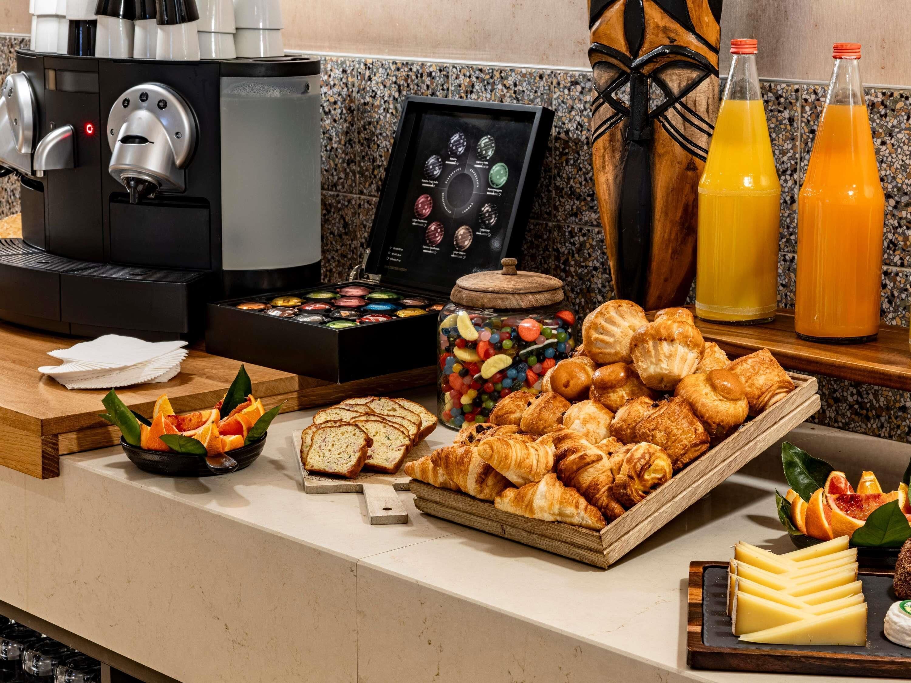 A breakfast buffet with pastries, bread, cheese, and a coffee machine.