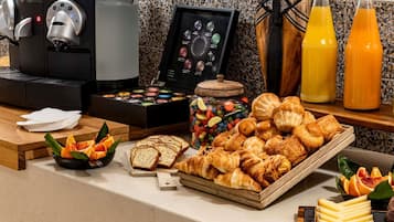 A breakfast buffet with pastries, bread, cheese, and a coffee machine.