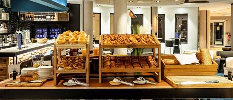 Morgenmadsbuffet med kager og brød, barstole og en bar med flasker.